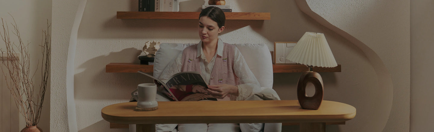 Woman sitting at a desk with a laptop, surrounded by shelves and decor.